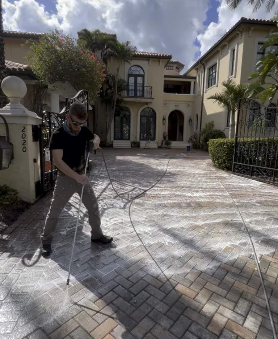 Surface cleaning in progress on a residential paver driveway